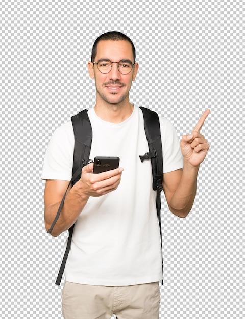 Estudiante feliz apuntando hacia arriba y usando un teléfono móvil