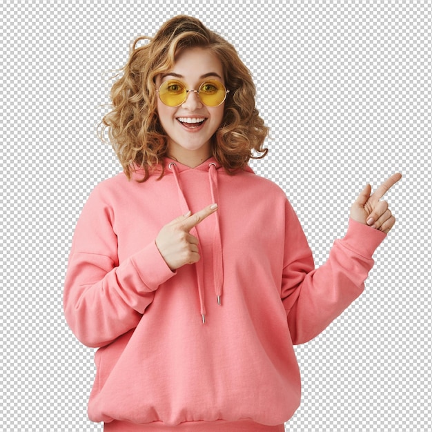 Excitada chica elegante de cabello rizado con gafas de sol apuntando a la derecha mostrando el camino