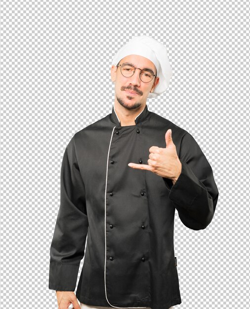 Felice giovane chef facendo un gesto di chiamare con la mano