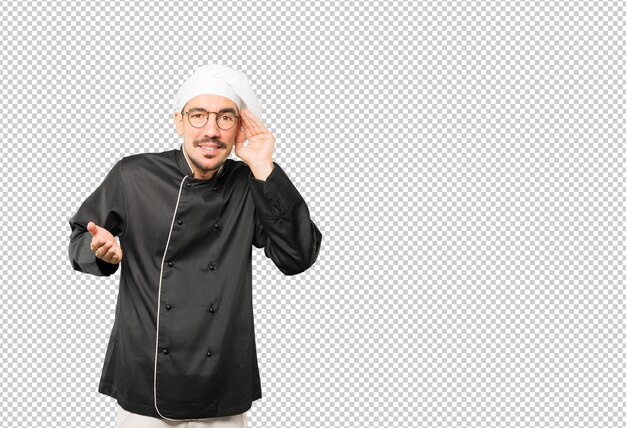 Felice giovane chef sorridente e facendo un gesto di provare a sentire qualcosa