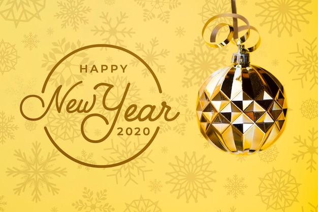 Feliz ano novo 2020 com bola de Natal dourada sobre fundo amarelo