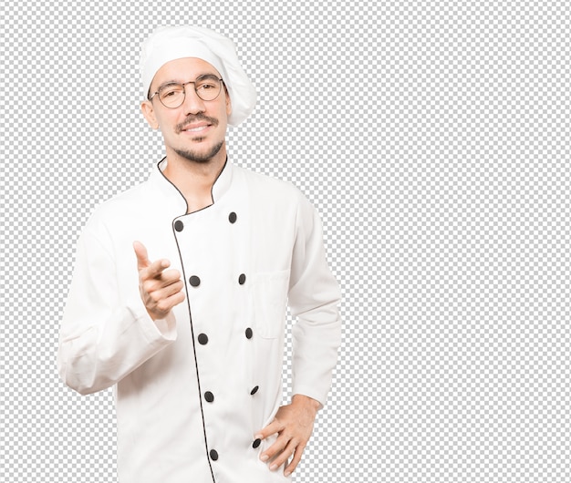 Feliz joven chef apuntando con su dedo