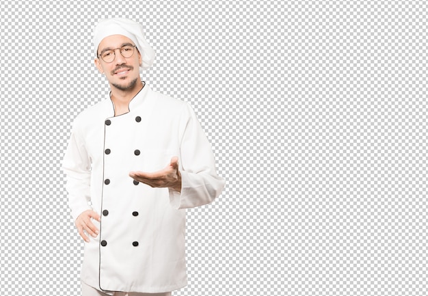 Feliz joven chef haciendo un gesto de bienvenida con la mano