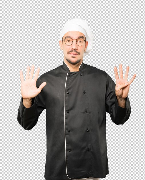 Feliz joven chef haciendo un gesto número nueve con sus manos