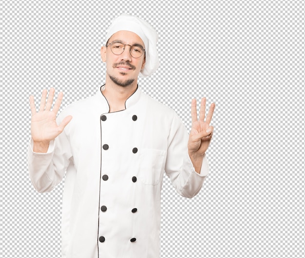 Feliz joven chef haciendo un gesto número ocho con sus manos