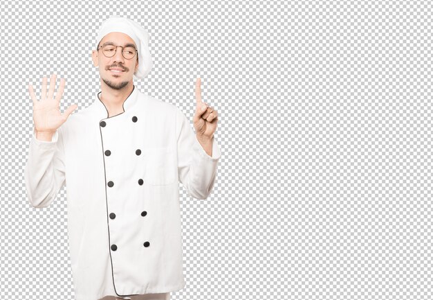 Feliz joven chef haciendo un gesto número seis con las manos