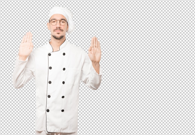 Feliz joven chef haciendo un gesto de parada con la palma de su mano
