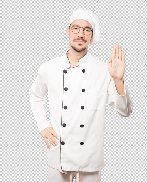 Feliz joven chef haciendo un gesto de parada con la palma de su mano