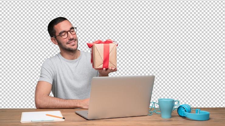 PSD feliz joven sentado en su escritorio y sosteniendo un regalo
