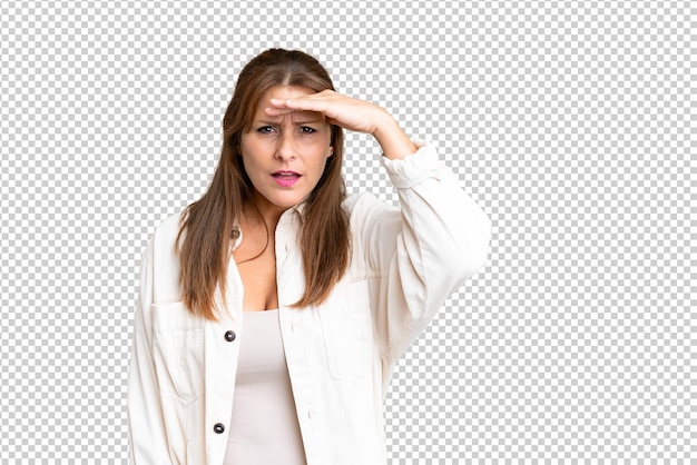 Femme d'âge moyen sur un fond isolé regardant loin avec la main pour regarder quelque chose