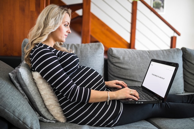 PSD femme enceinte sur le canapé à l'aide d'ordinateur