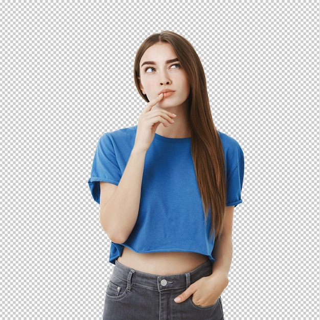 Une femme européenne créative, intelligente et réfléchie, attrayante, en haut bleu à la mode, faisant un geste avec le doigt sur la lèvre inférieure, levant les sourcils et regardant vers le haut, pensant, faisant un choix en tête.