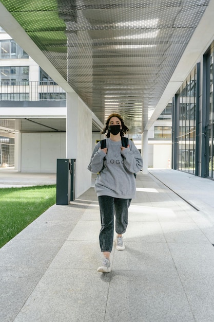 une femme marche sur un trottoir avec une caméra devant un bâtiment