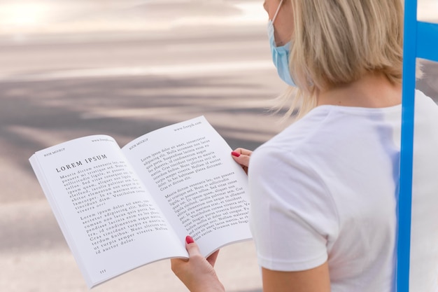 Femme avec masque sur livre de lecture de rue