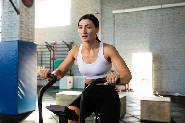 Une femme s'entraîne sur un vélo aérien dans un gymnase
