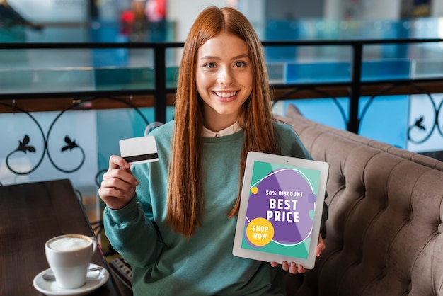 Femme souriante avec une carte de crédit et une tablette dans ses mains