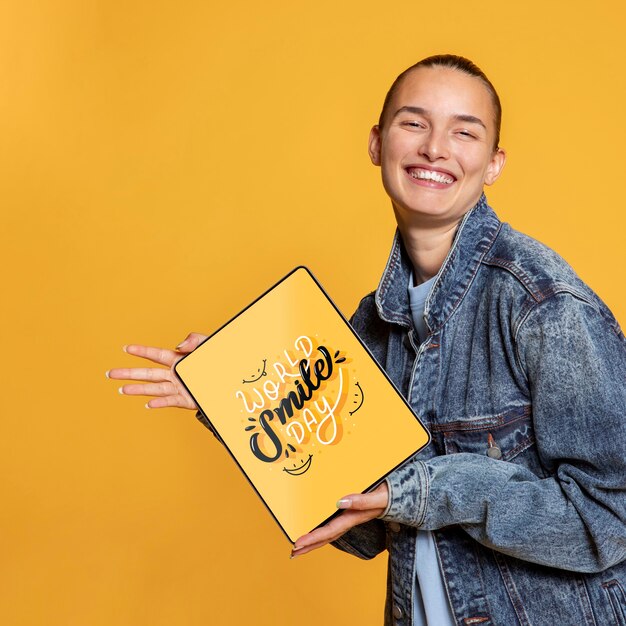 Femme souriante et s'amusant tout en tenant une maquette de tablette