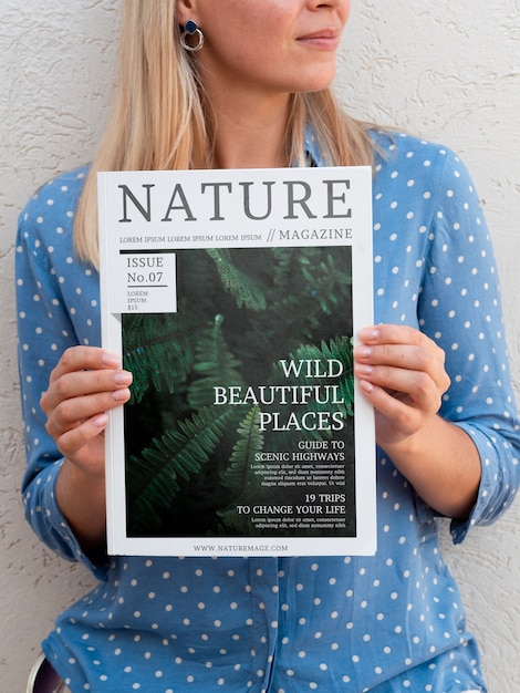 Femme tenant à deux mains un magazine sur la nature