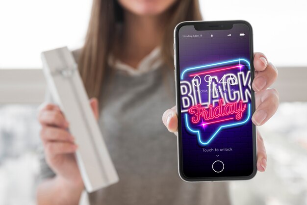 Femme tenant une maquette de smartphone avec concept de vendredi noir