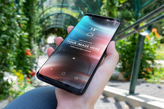 Femme tenant un smartphone moderne dans une maquette de parc