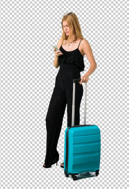 PSD fille blonde voyageant avec sa valise envoyant un message ou un email avec le téléphone portable