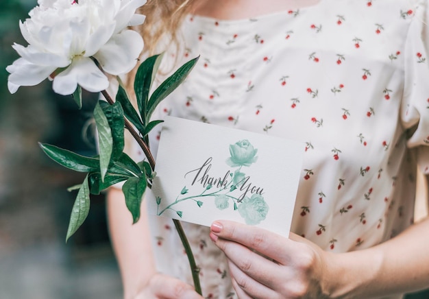 Fille avec une fleur de snowboard paeonia blanche et une carte de maquette