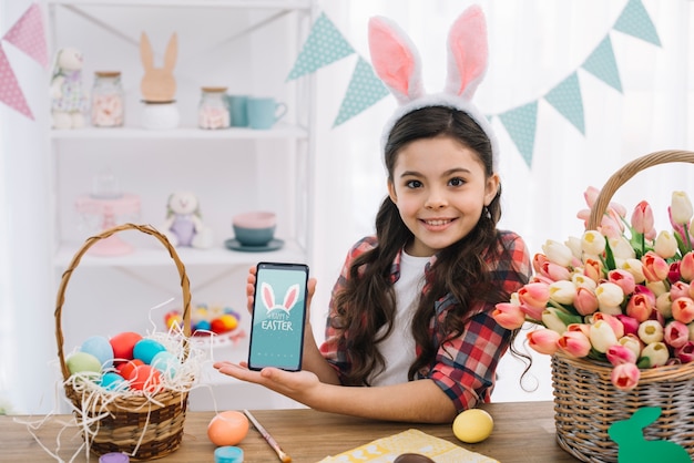 Fille avec une maquette de smartphone le jour de Pâques