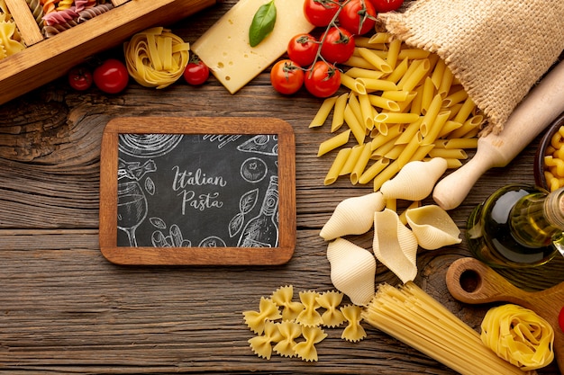 Flach lag ungekochte Pasta-Auswahl und Tomaten mit Tafel-Mock-up