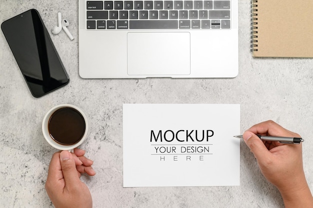 Flach liegend Draufsicht Mockup Leeres Papier mit Handhaltestift und Kaffeetasse auf dem Schreibtisch mit Labtop-Smartphone-Kopfhörer-Notebook und Pflanze Leerer Platz zum Einfügen Ihres Designs