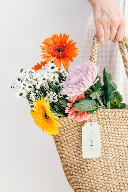 Flores tropicales de colores en una bolsa tejida con una maqueta de tarjeta