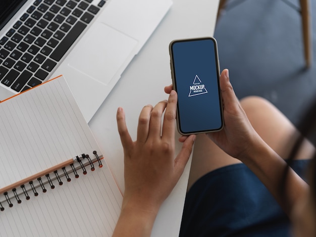 Foto aérea de mão usando simulação de smartphone na mesa de trabalho com laptop e notebook