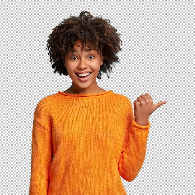 Foto de uma mulher afro-americana alegre e encantada com o cabelo nítido mostra um espaço em branco feliz em anunciar um item à venda usa um jumper laranja demonstra onde a loja de roupas está localizada