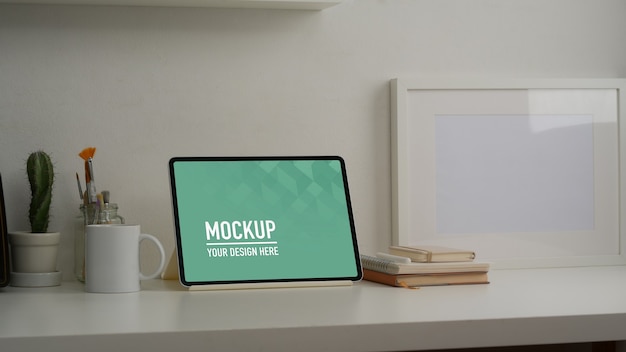 Foto recortada da mesa de trabalho com simulação de tablet, artigos de papelaria e decorações na sala de home office