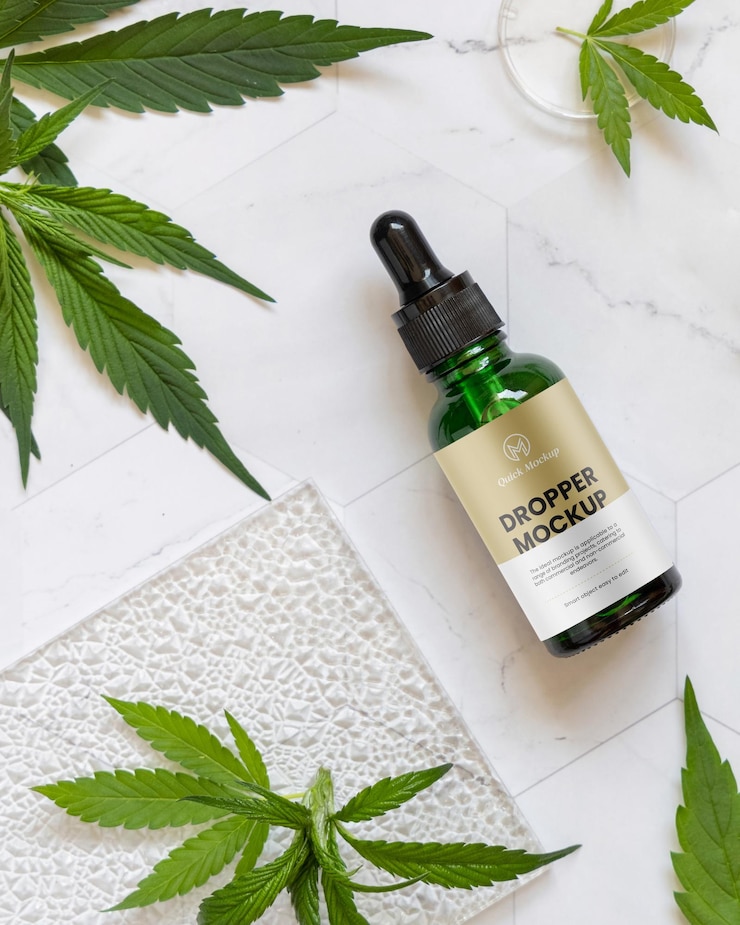 PSD frasco cuentagotas con etiqueta en blanco cerca de hojas verdes de cannabis en mesa blanca
