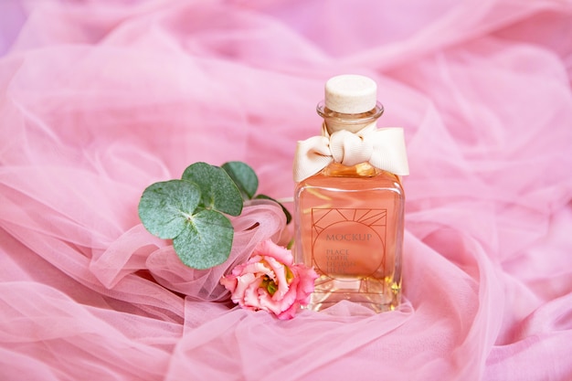 PSD frasco de perfume com flores na superfície rosa têxtil