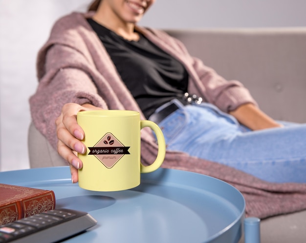 Frau auf der Couch mit gelbem Becher