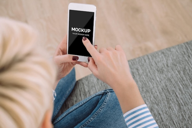 Frau, die Smartphone-Modell beim Sitzen auf der Couch verwendet