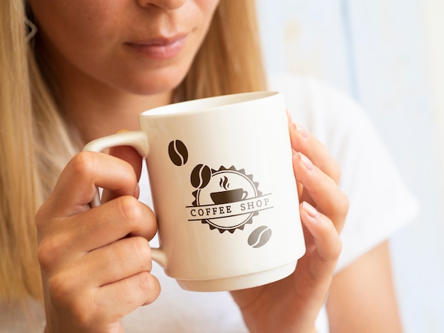 Frau, die von einem Kaffeetassenmodell trinken will