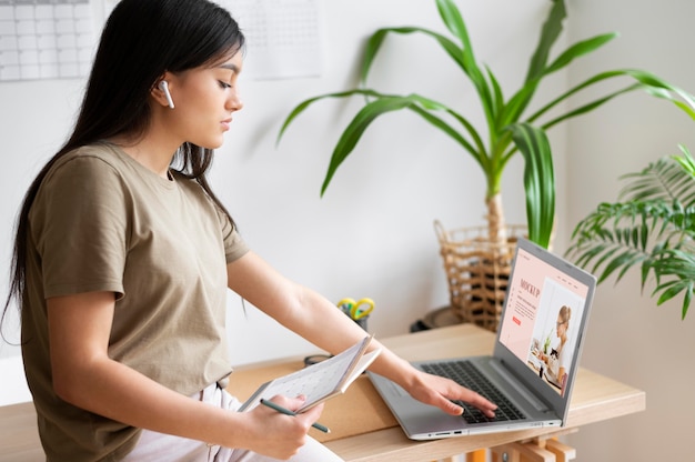 Frau, die von zu hause aus mit laptop arbeitet und notizen macht