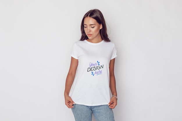 Frau mit einem weißen T-Shirt-Mockup vor einem weißen Hintergrund