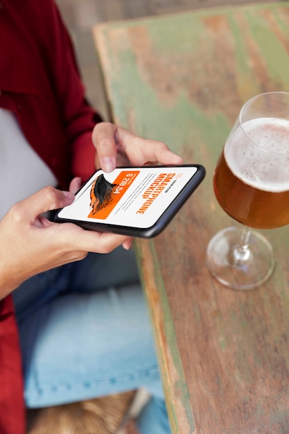 Frau mit Mock-up-Smartphone im Freien mit einem Glas Getränk