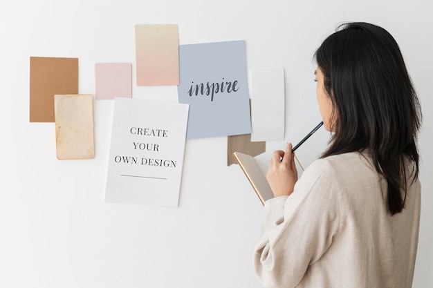 Frau mit Papiermockups an einer Wand