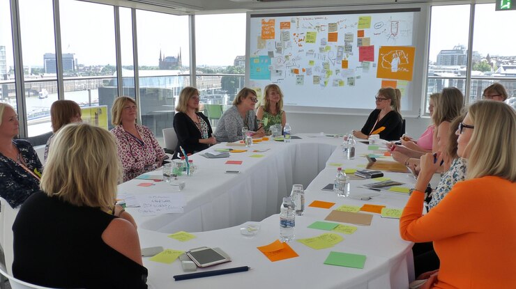 PSD frauen in einem brainstorming-treffen um einen tisch mit klebrigen notizen und einem großen whiteboard