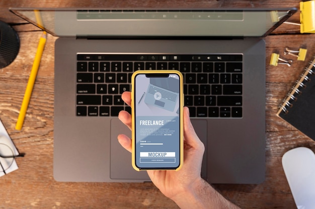 PSD freelancer travaillant sur un ordinateur portable tout en tenant une maquette de téléphone