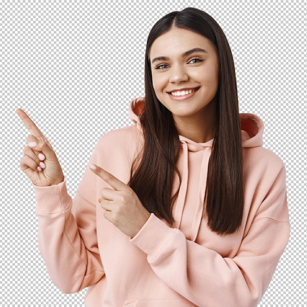 Fröhliche junge Frau zeigt Copy-Raum, weist mit den linken Fingern auf Banner oder Werbung, demonstriert ein gutes Produkt, weiße Wand