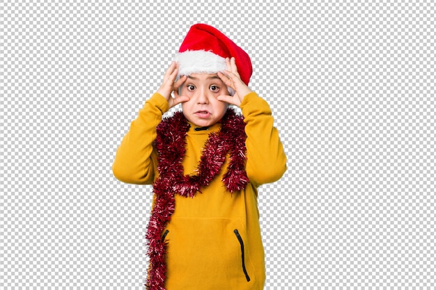 PSD garotinho, comemorando o dia de natal, usando um chapéu de papai noel, mantendo os olhos abertos para encontrar uma oportunidade de sucesso.