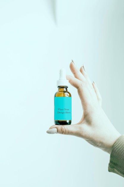 Garrafa de perfume dourada com rótulo azul mantida na mão Mockup PSD