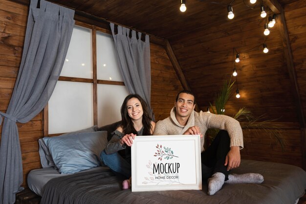 Gente feliz sentada en la cama y sosteniendo una maqueta de decoración del hogar