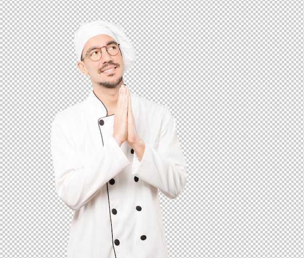 Gesto de oración de joven chef preocupado