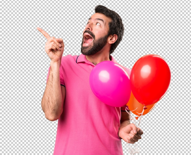 Giovane bello che tiene palloncini e pensando